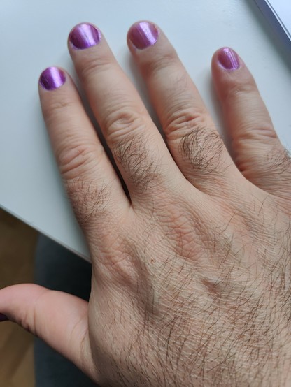 Mano peluda con las uñas pintadas de lila